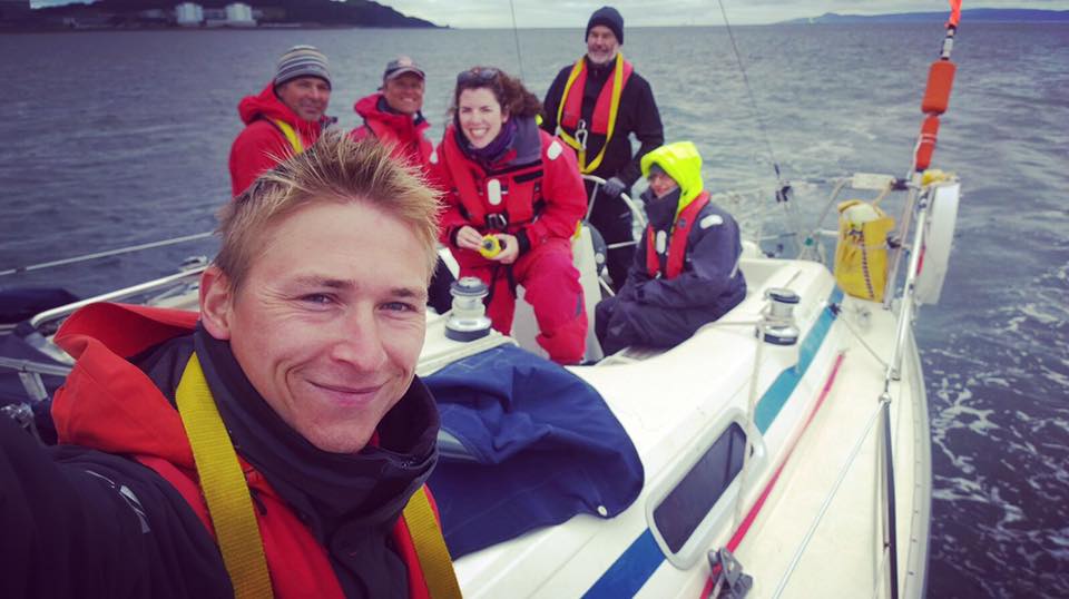 Sailing instructor and crew members smiling together during a practical sailing course